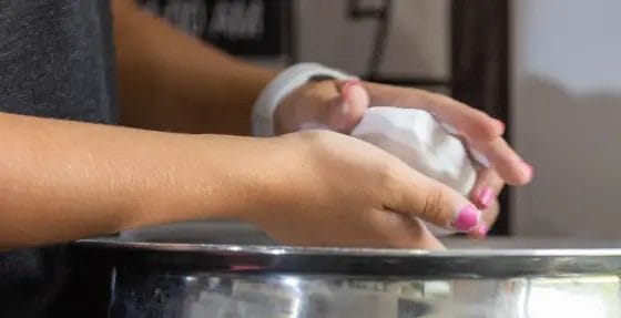 Person applying chalk to hands over a gym chalk bowl before a workout at Relentless Athletics
